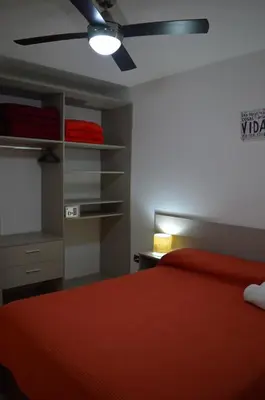a bedroom with a red bed and a ceiling fan at Kawsay Complejo de Cabañas in San Antonio de Arredondo