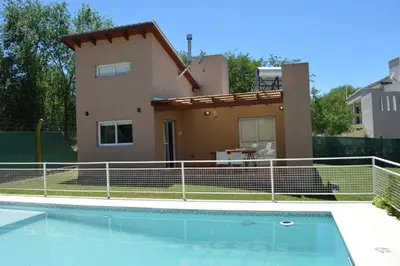 a villa with a swimming pool in front of a house at Kawsay Complejo de Cabañas in San Antonio de Arredondo