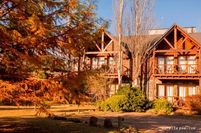 a large wooden house with trees in front of it at Chamonix Posada & Spa in Villa General Belgrano