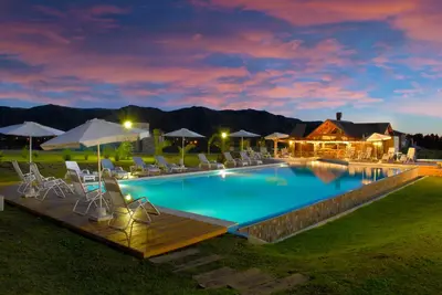 a large swimming pool with chairs and umbrellas at Chamonix Posada & Spa in Villa General Belgrano