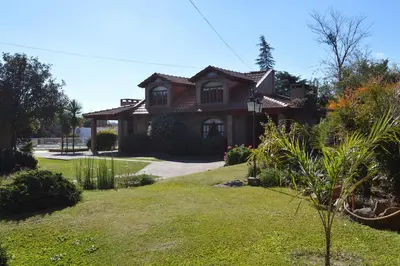 a house with a grass yard in front of it at Cabañas La Aldea in Villa Carlos Paz