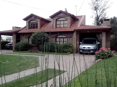 a house with a van parked in front of it at Cabañas La Aldea in Villa Carlos Paz