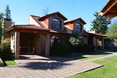 a brick house with a red roof at Cabañas La Aldea in Villa Carlos Paz