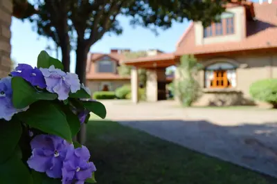 a house with purple flowers in front of a yard at Cabañas La Aldea in Villa Carlos Paz