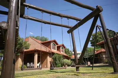 a house with a swing set in the yard at Cabañas La Aldea in Villa Carlos Paz