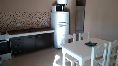 a kitchen with a table and a white refrigerator at Merlo Centro Aparts in Merlo