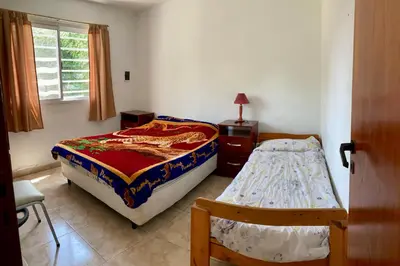 a bedroom with two beds and a table and a window at Aires de las Sierras in Villa Carlos Paz