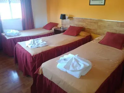 three beds in a hotel room with towels on them at Hotel Aoma Villa Carlos Paz in Villa Carlos Paz