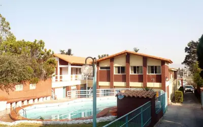 a building with a swimming pool in front of a house at Hotel Aoma Villa Carlos Paz in Villa Carlos Paz