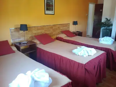 three beds in a hotel room with towels on them at Hotel Aoma Villa Carlos Paz in Villa Carlos Paz