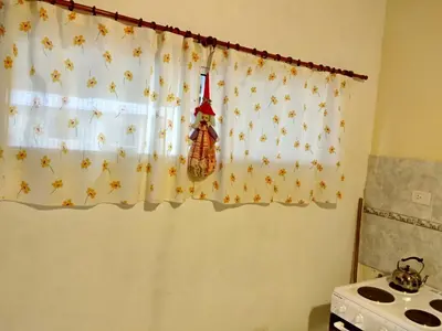 a kitchen window with a curtain with autumn leaves on it at Cabañas Misky Wayra in San Francisco del Monte de Oro