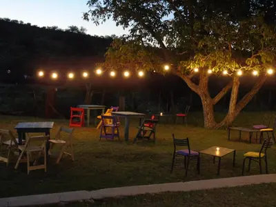a group of tables and chairs under a tree with lights at al otro lado del río in San Francisco del Monte de Oro