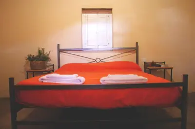 a red bed with two towels on it with a window at al otro lado del río in San Francisco del Monte de Oro