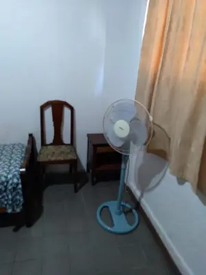 a room with a fan and a chair and a bed at Departamentos Calamuchita in Santa Rosa de Calamuchita
