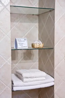 a glass shelf in a bathroom with towels on it at Del Arroyo Cabañas in Villa General Belgrano