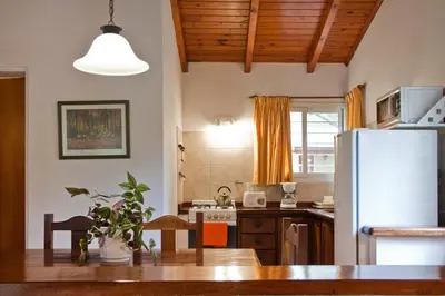 a kitchen with a white refrigerator and a table at Del Arroyo Cabañas in Villa General Belgrano
