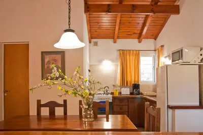 a kitchen with a table with a vase of flowers on it at Del Arroyo Cabañas in Villa General Belgrano