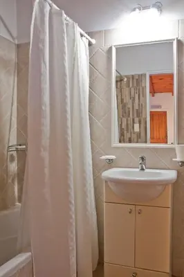 a bathroom with a sink and a shower curtain at Del Arroyo Cabañas in Villa General Belgrano