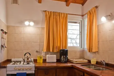 a kitchen with a sink and a stove and a window at Del Arroyo Cabañas in Villa General Belgrano