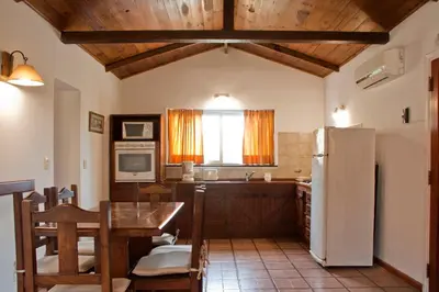 a kitchen with a table and a refrigerator at Del Arroyo Cabañas in Villa General Belgrano