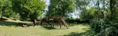 a wooden playground in a park with trees at Del Arroyo Cabañas in Villa General Belgrano