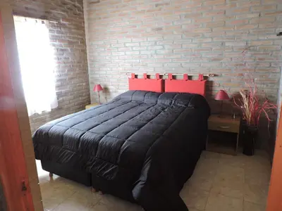 a bedroom with a bed and a brick wall at CABAÑAS LOS COCKERS in Villa General Belgrano