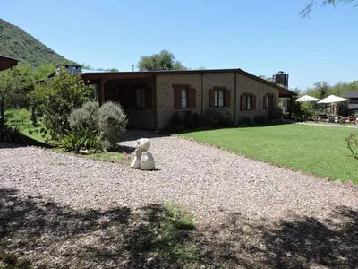 a teddy bear sitting on the gravel in front of a house at CABAÑAS LOS COCKERS in Villa General Belgrano