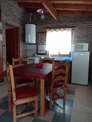 a kitchen with a table and chairs and a refrigerator at CABAÑAS LOS COCKERS in Villa General Belgrano
