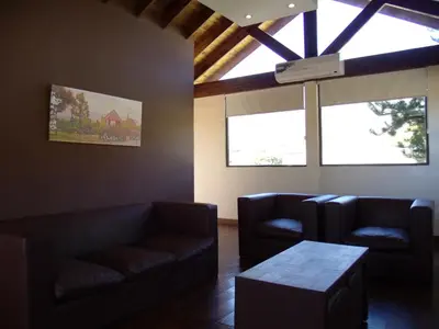 a living room with couches and a table and windows at Altos del Sol - Spa & Resort in Merlo
