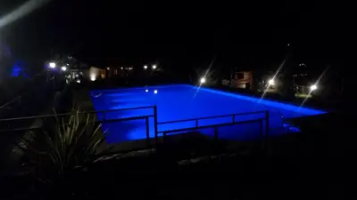 a swimming pool lit up at night with lights at Altos del Sol - Spa & Resort in Merlo