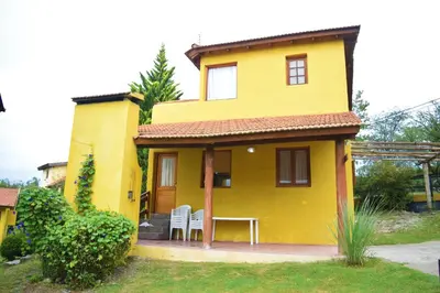 a yellow house with a table and chairs in it at Cabañas Wairoa Haus in Villa General Belgrano