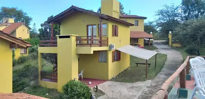 a yellow house with a hammock in front of it at Cabañas Wairoa Haus in Villa General Belgrano