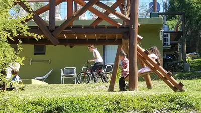 a woman and children playing on a playground at Cabañas Wairoa Haus in Villa General Belgrano
