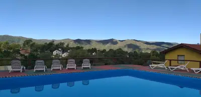 a view of a swimming pool with chairs and mountains at Cabañas Wairoa Haus in Villa General Belgrano