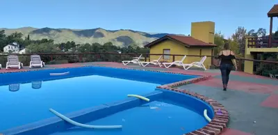 a woman walking next to a swimming pool at Cabañas Wairoa Haus in Villa General Belgrano
