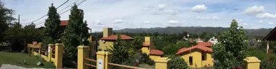 a yellow house with a fence in a field at Cabañas Wairoa Haus in Villa General Belgrano