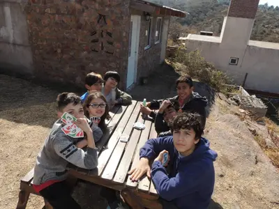 a group of young people sitting on a picnic table at Cabañas La Rústica in Bialet Massé