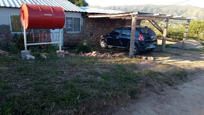 a car parked under a pergola next to a house at Cabañas La Rústica in Bialet Massé