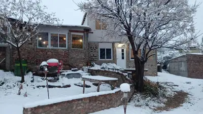 a house covered in snow with a picnic table in the yard at Cabañas La Rústica in Bialet Massé