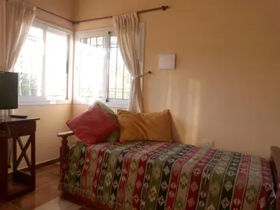 a bedroom with a bed with colorful sheets and a window at El Pinar - Hospedaje Serrano in Tanti