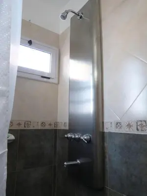 a shower with a glass door and a window at El Pinar - Hospedaje Serrano in Tanti