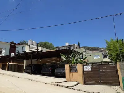 a parking lot with cars parked in front of a building at LA FOGLIA departamentos in Villa Carlos Paz