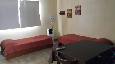 a room with two beds and a table and a table sidx sidx sidx at LA FOGLIA departamentos in Villa Carlos Paz