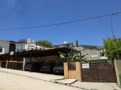 a parking lot with cars parked in front of a building at LA FOGLIA departamentos in Villa Carlos Paz
