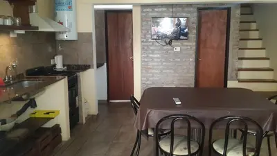 a kitchen with a table with chairs and a television on the wall at LA FOGLIA departamentos in Villa Carlos Paz