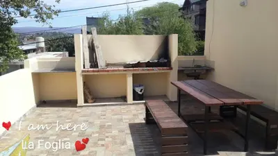 a bench and a table on the side of a building at LA FOGLIA departamentos in Villa Carlos Paz