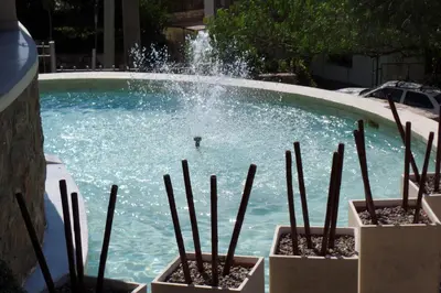 a fountain in a pool with a person in it at Villa La Font Apart Hotel & Spa in Villa Carlos Paz
