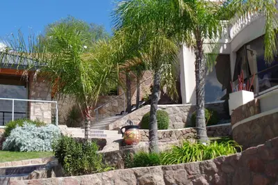a house with palm trees and a fire hydrant at Villa La Font Apart Hotel & Spa in Villa Carlos Paz