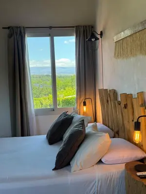 a bedroom with a bed with pillows and a window at Punta Piedra cabañas & suites in Los Reartes