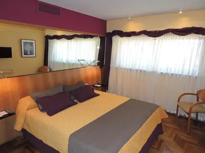a bedroom with a large bed and curtains at King David Flat Hotel - Argentina in Cordoba